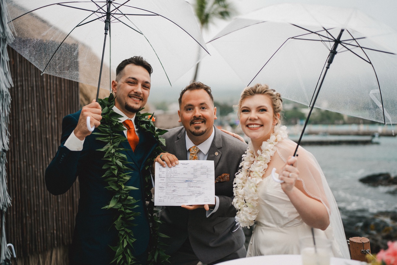 Peter celebrating with newlyweds beneath clear umbrellas